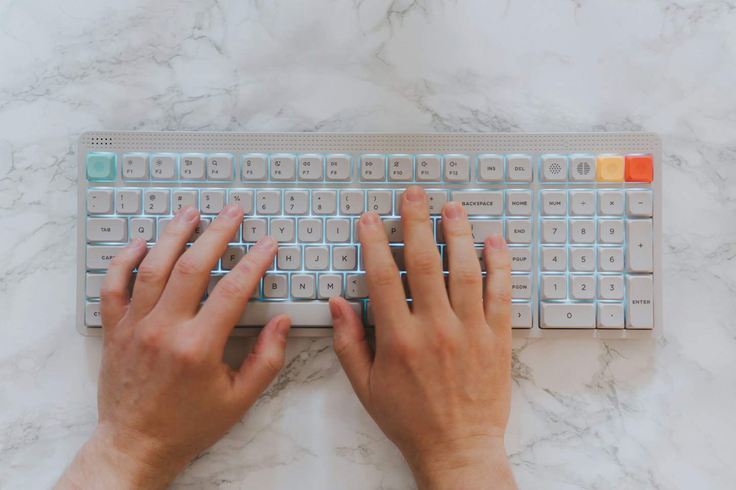 Mani pronte a digitare su una tastiera meccanica illuminata.